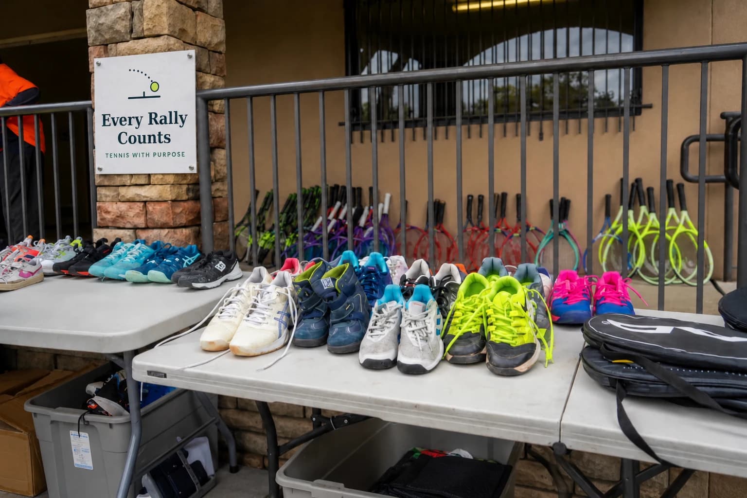 Donated shoes and racquets laid out beside an Every Rally Counts sign.